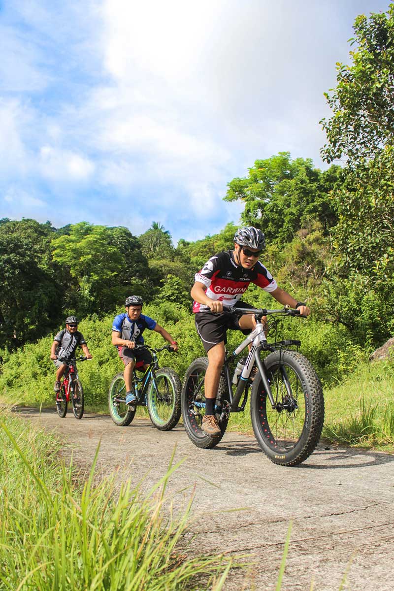 three men riding their bikes on the road