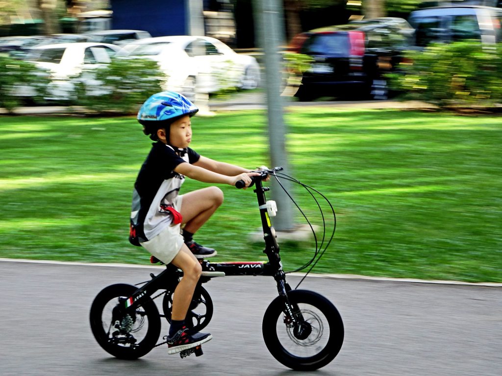 A boy riding a bike while wearing one of the best kids' bike helmets in blue