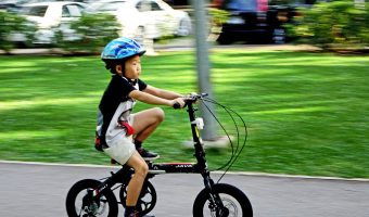 A boy riding a bike while wearing one of the best kids' bike helmets in blue